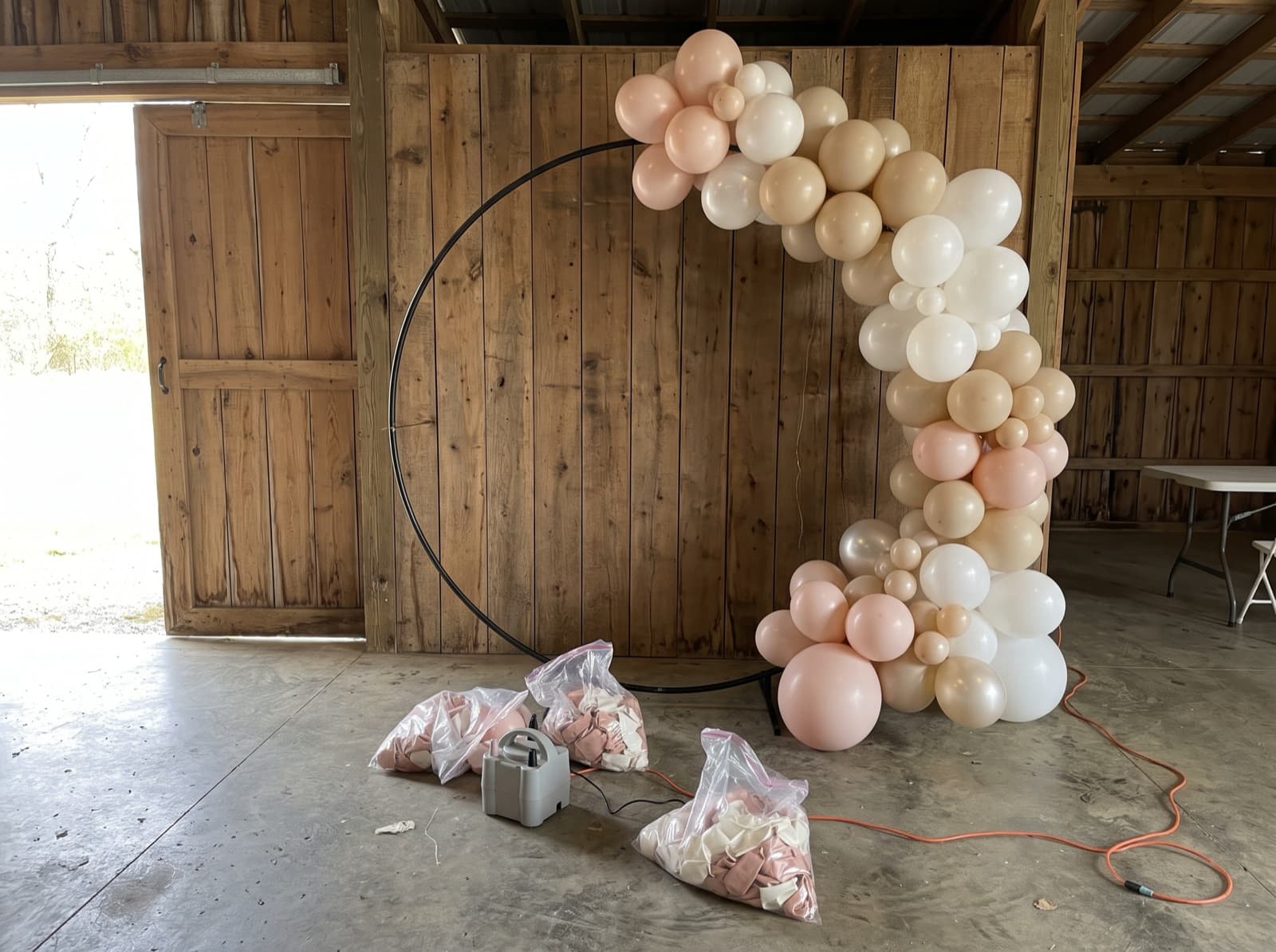 Organic balloon garland half-built on an arch frame before an event