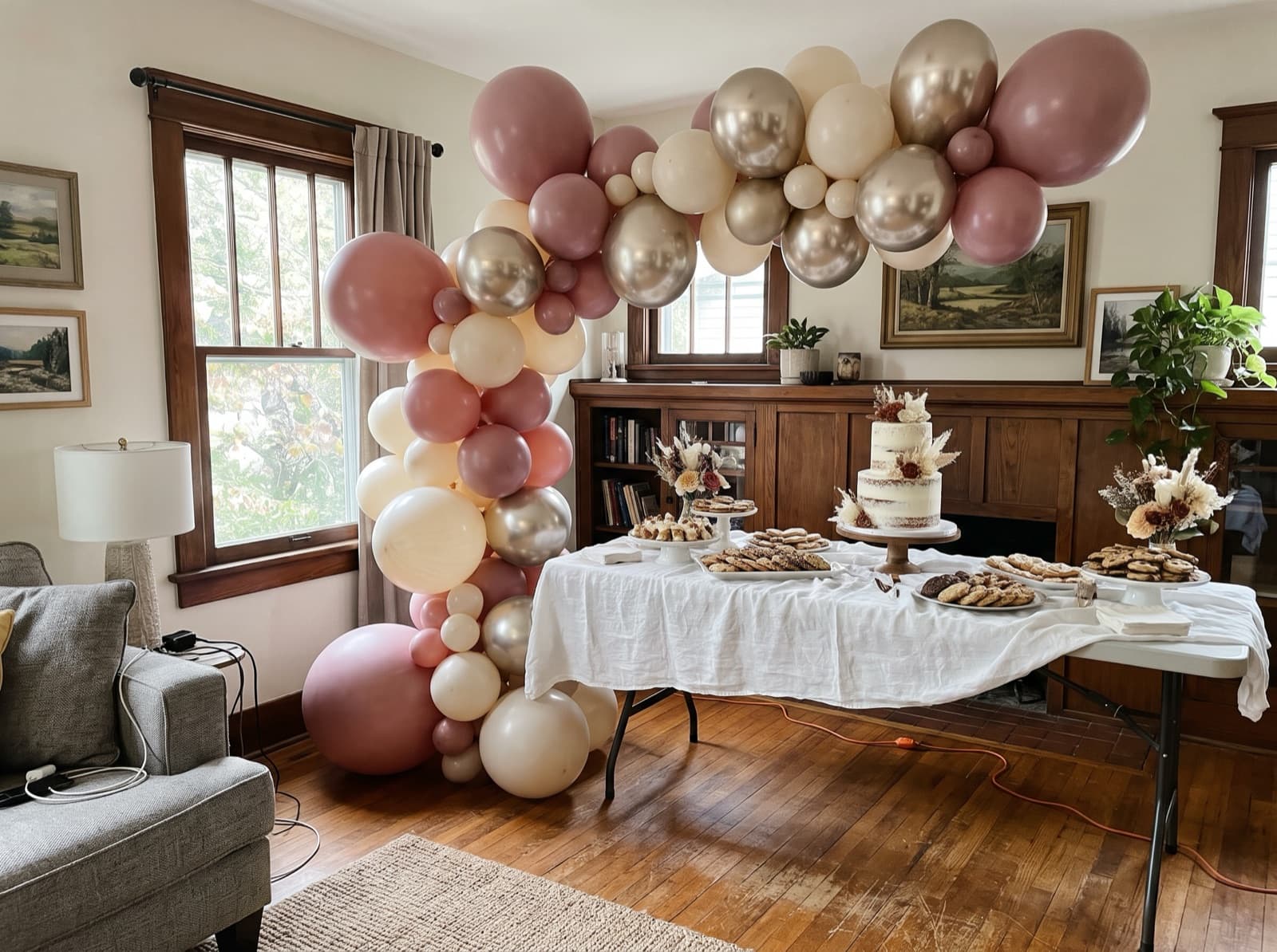 Organic balloon arch in dusty rose, ivory and champagne over a dessert table in a Nashville living room