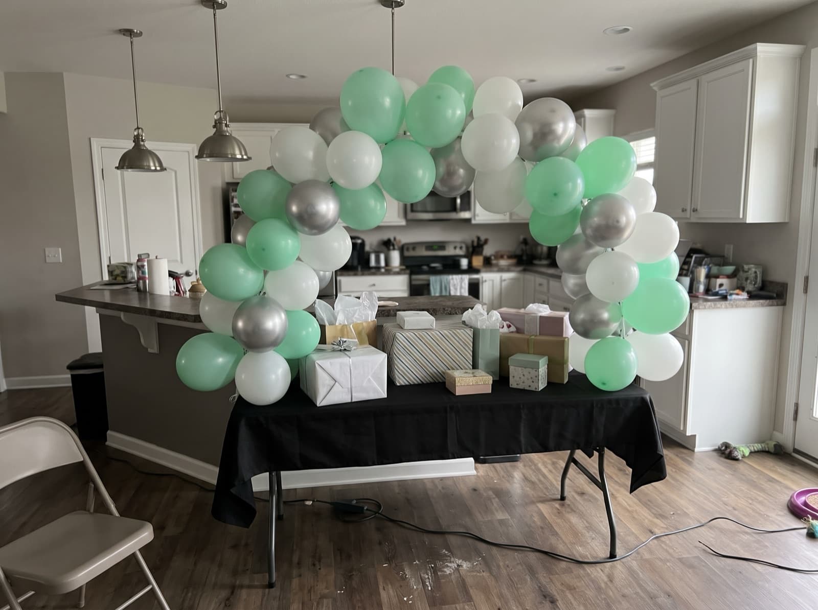 Mini tabletop balloon arch in mint, white and silver over a gift table