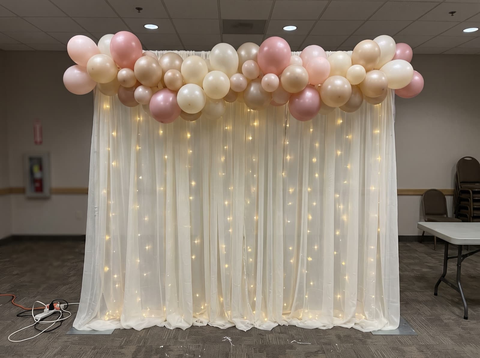 Draped ivory backdrop with balloons and lights
