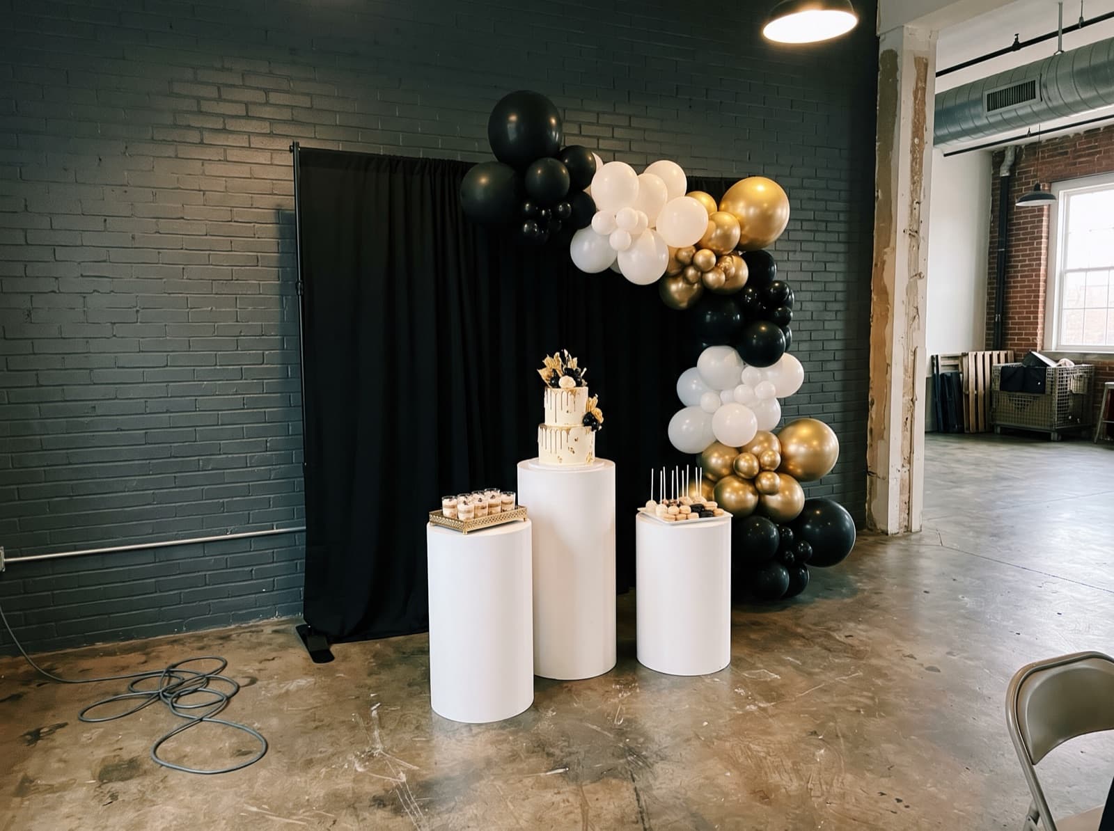 Black backdrop with pedestals and a cake table
