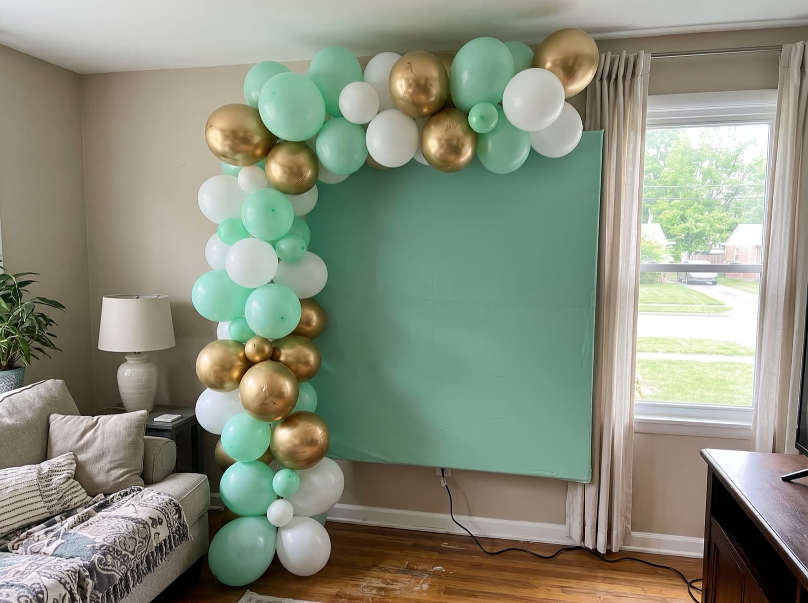 Square mint backdrop with a balloon garland up one side