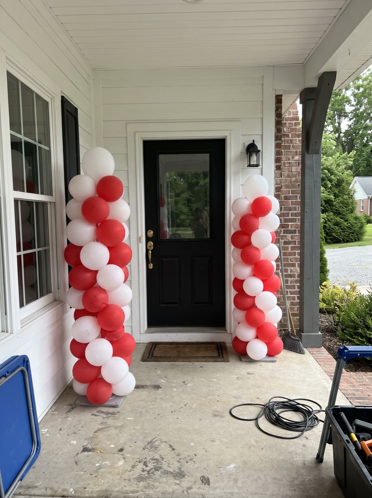 Pair of red and white spiral balloon columns at a farmhouse front door