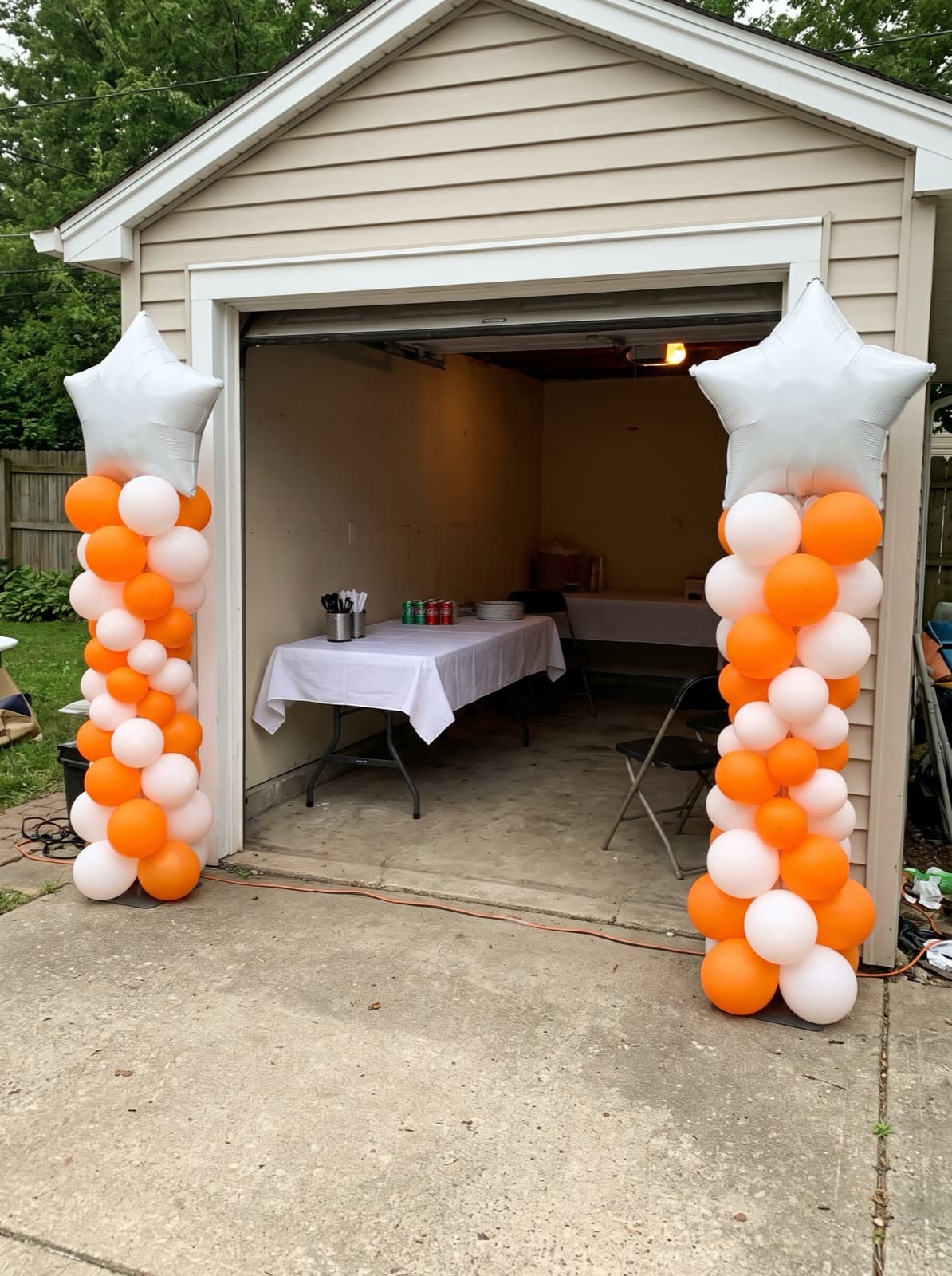 Orange and white balloon columns with star toppers at a grad party