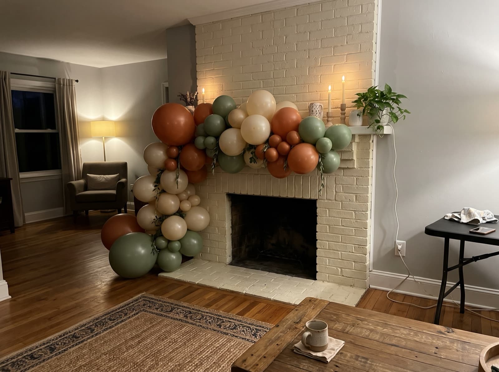 Organic balloon garland in terracotta, cream and sage along a brick fireplace mantel in a Nashville home