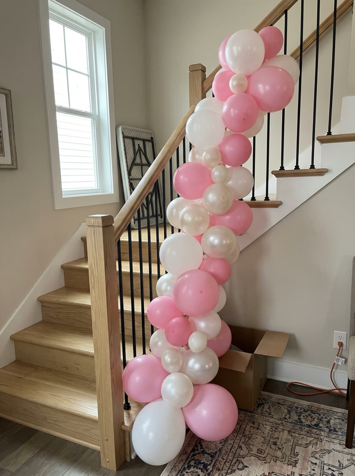 Pink, white and pearl balloon garland down a townhouse stair railing