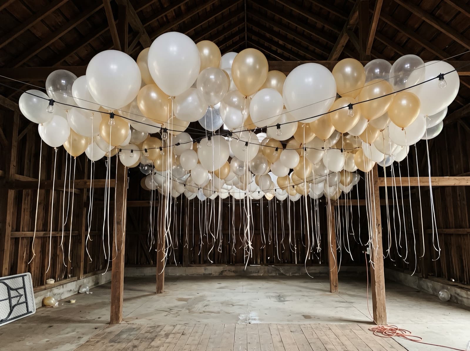 Balloon ceiling of white, clear and champagne balloons over a dance floor in a Nashville barn venue