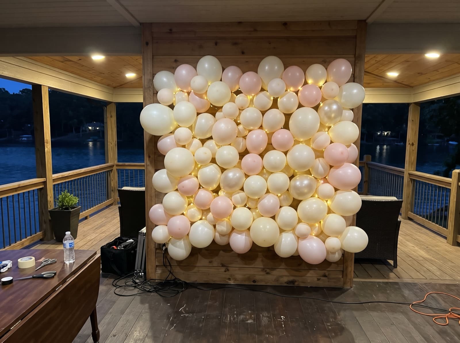 Balloon wall with string lights on a covered lake house deck